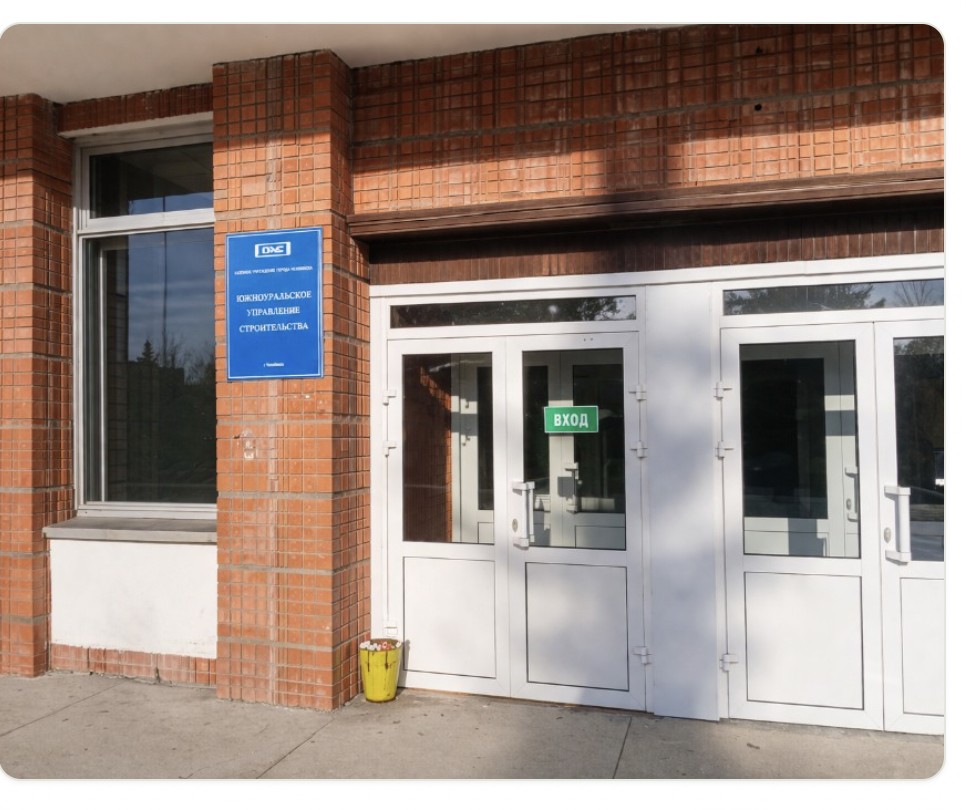 Кирпичный фасад здания: вход с белыми дверями и синим информационным указателем